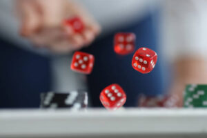 Man throws red dice on table and chips. Casino game and luck
